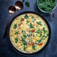 Photo of pasta e fagioli soup in bowl with kale and gold spoons