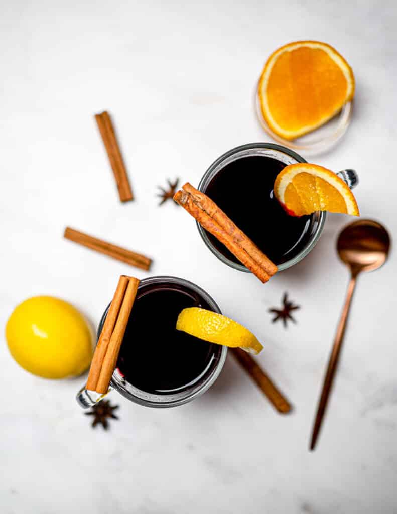 Two glasses of mulled wine on white table with lemon and cinnamon sticks