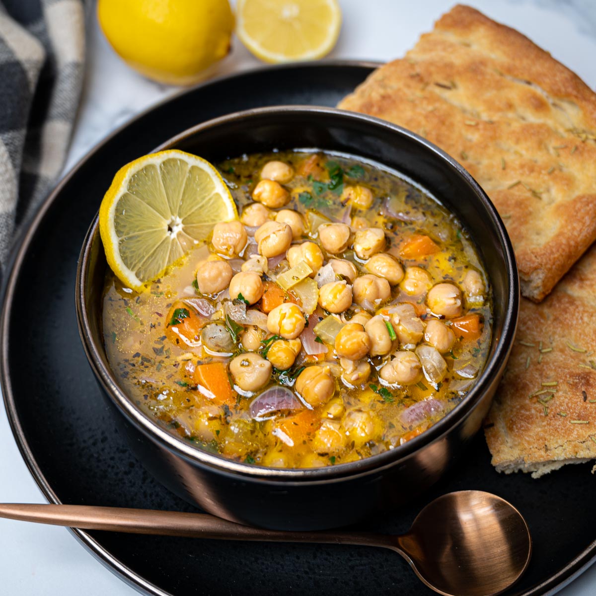 Photo of a black bowl of chickpea soup with lemon