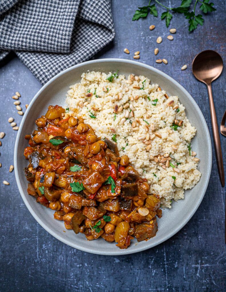 A bowl of vegan aubergine tagine with couscous on the side