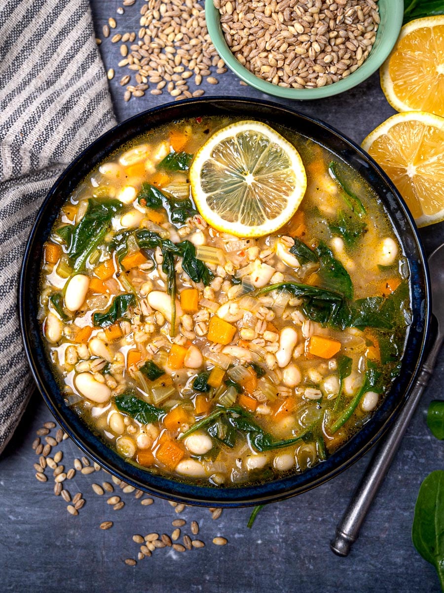 A bowl of vegan soup with beans, spinach and lemon