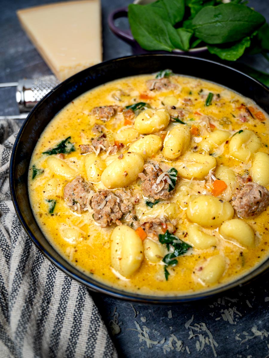 A bowl of gnocchi soup with spinach and sausage