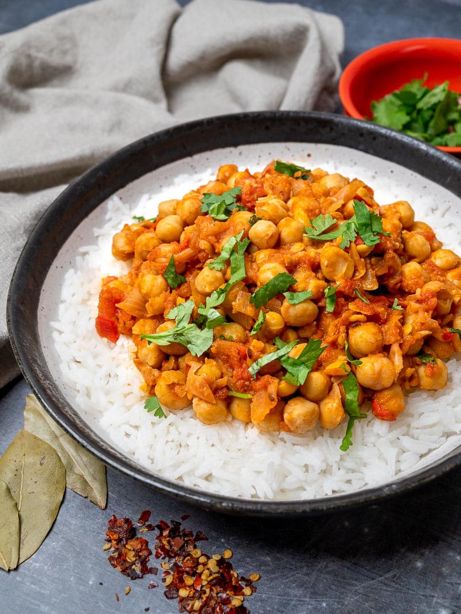 A bowl of curry with chickpeas over rice and topped with coriander