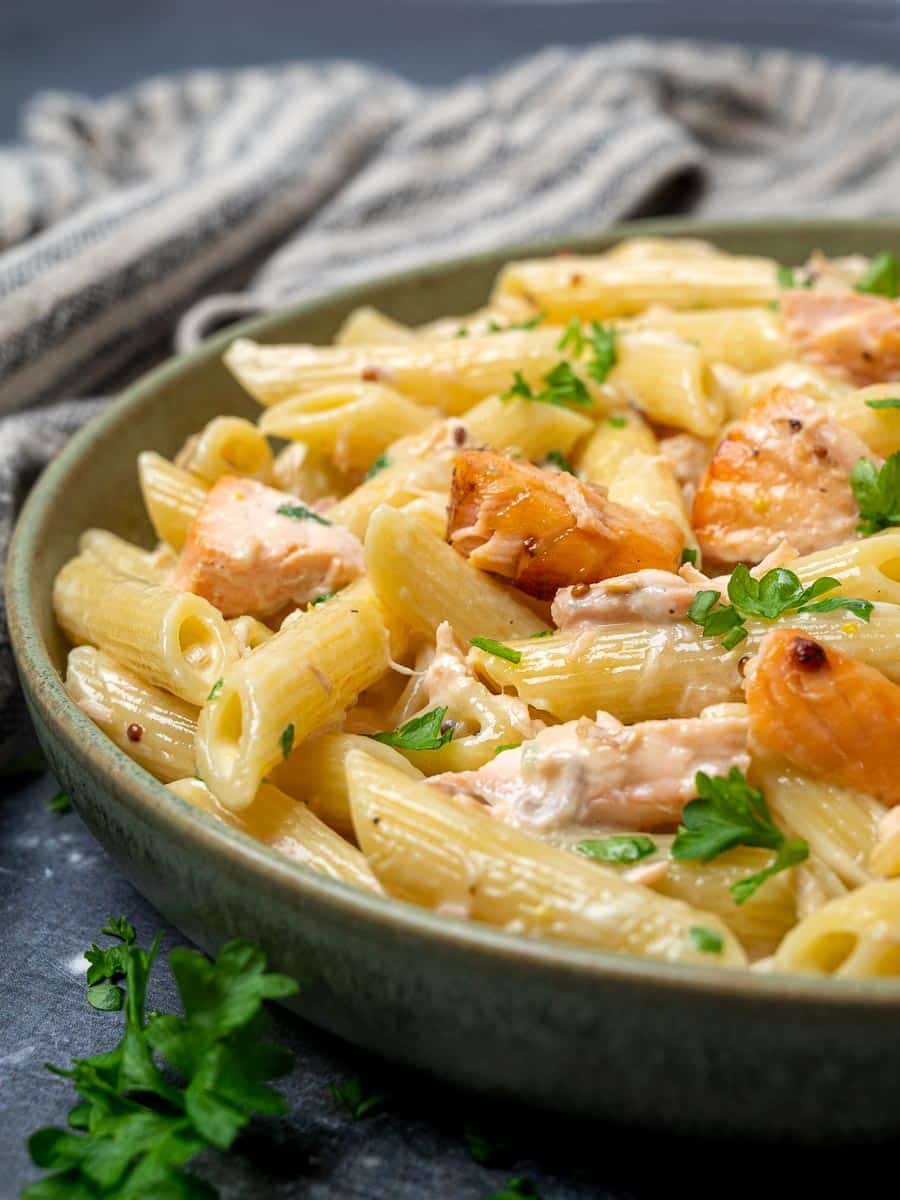 Close up photo of a bowl of honey mustard salmon pasta with parsley