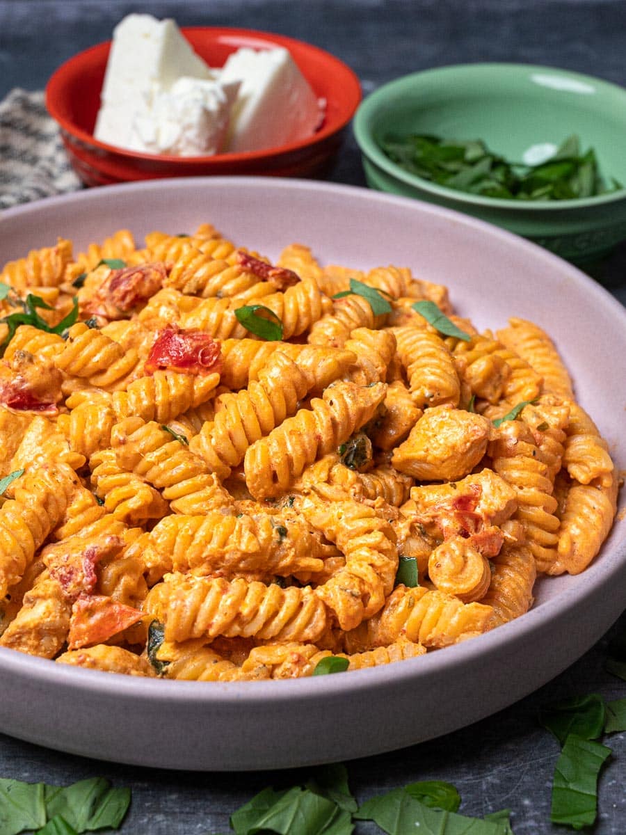 Close up photo of a bowl of chicken pasta with feta and basil 