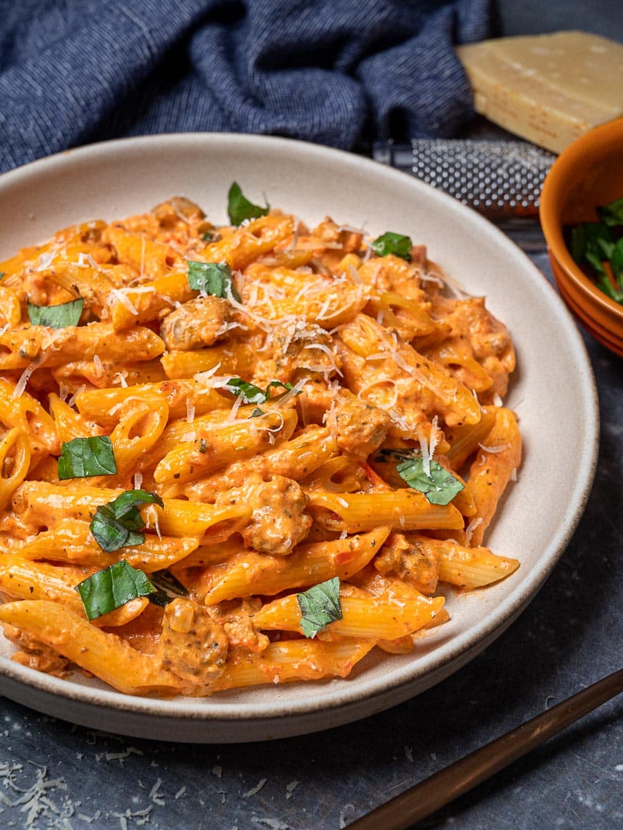 A plate of sausage pasta with parmesan on top