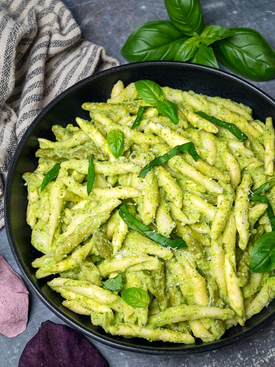 A bowl of green pasta sauce with basil