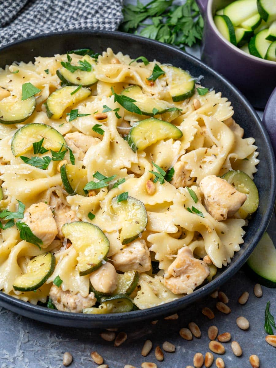 A close-up photo of a bowl of chicken pasta with zucchini