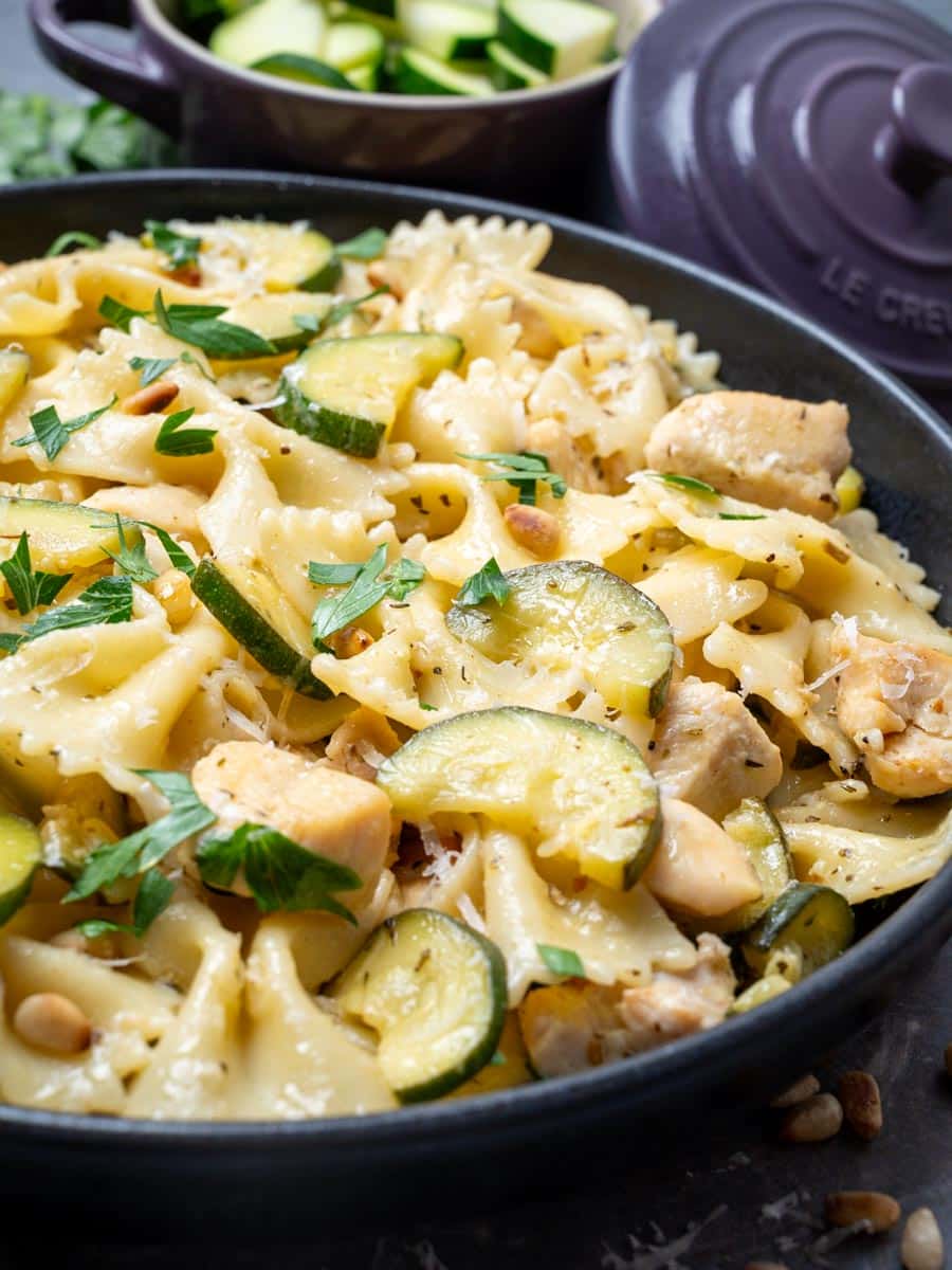 A close up photo of a bowl of farfalle pasta with chicken and zucchini