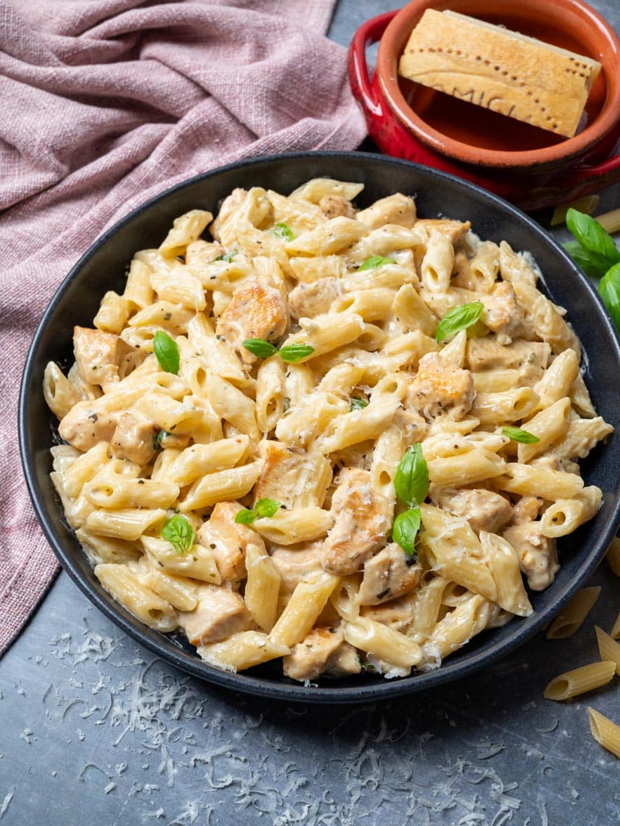 A photo of a bowl of penne with chicken in a creamy sauce