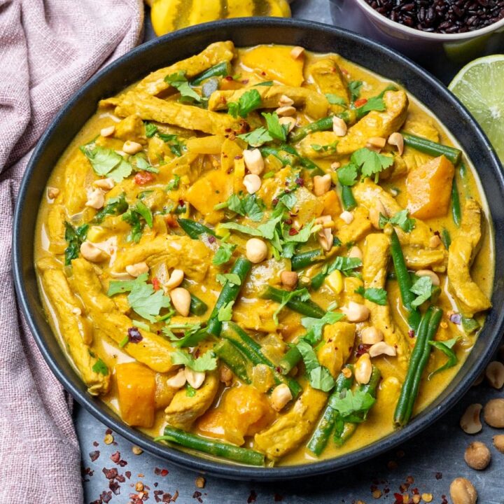 A bowl of coconut pork curry with peanuts and fresh coriander