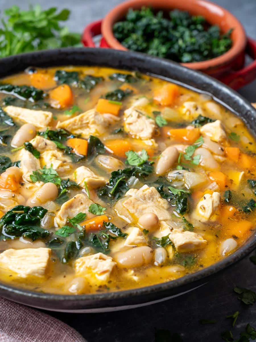 A close up photo of a bowl of soup with chicken and beans.