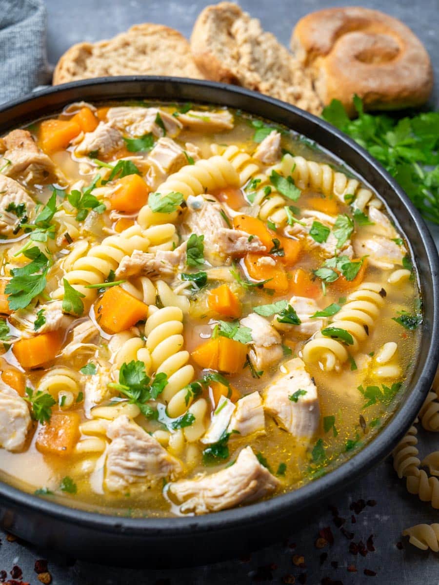 A close up photo of a bowl of turkey noodle soup.