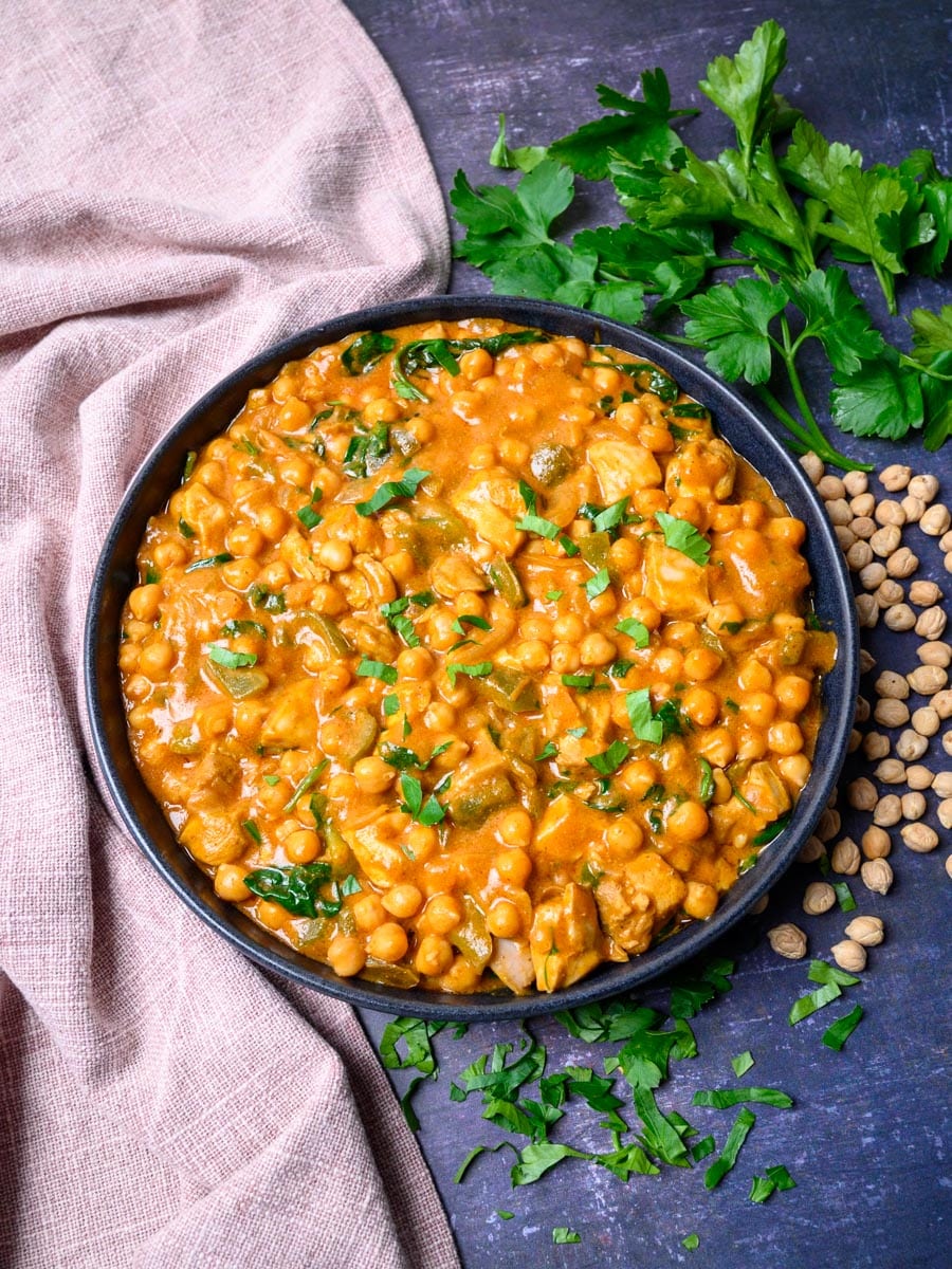 A bowl of chicken curry with chickpeas and coconut milk.