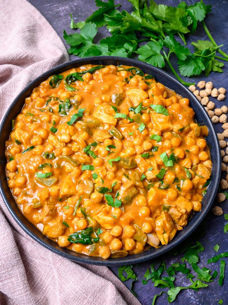 A bowl of curry with cilantro on the side.