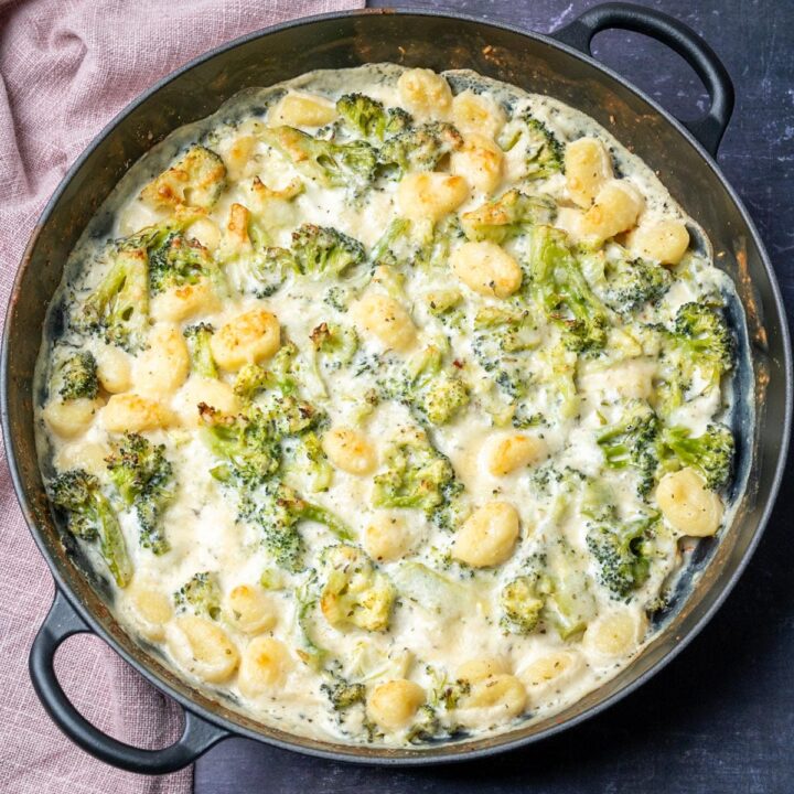 A baking dish with creamy gnocchi and broccoli.