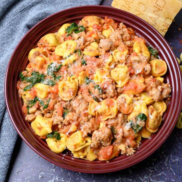 A bowl of tortellini with Italian sausage.