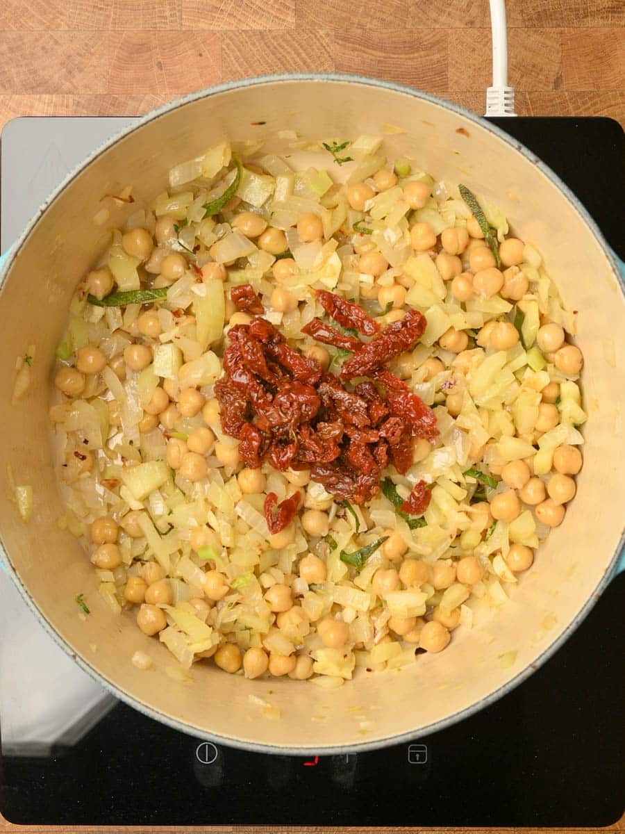 adding sundried tomatoes to a kale tortellini soup