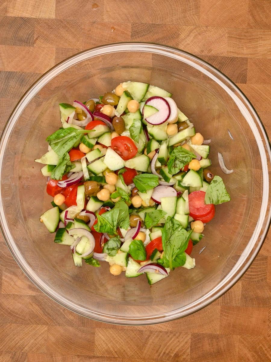 adding basil to a Mediterranean Cucumber Tomato Salad