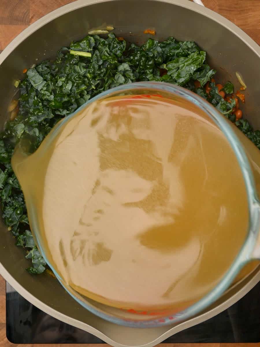 adding stock to a bean and potato soup
