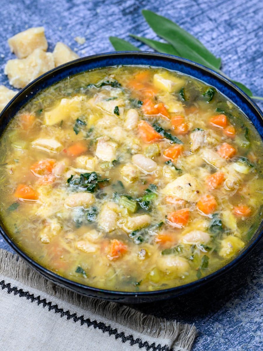 Close-up photo of a bowl of chicken soup with beans and parmesan