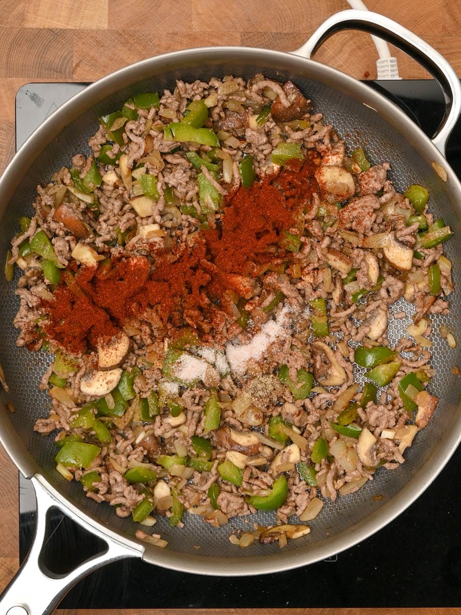 adding spices to a philly cheesesteak pasta