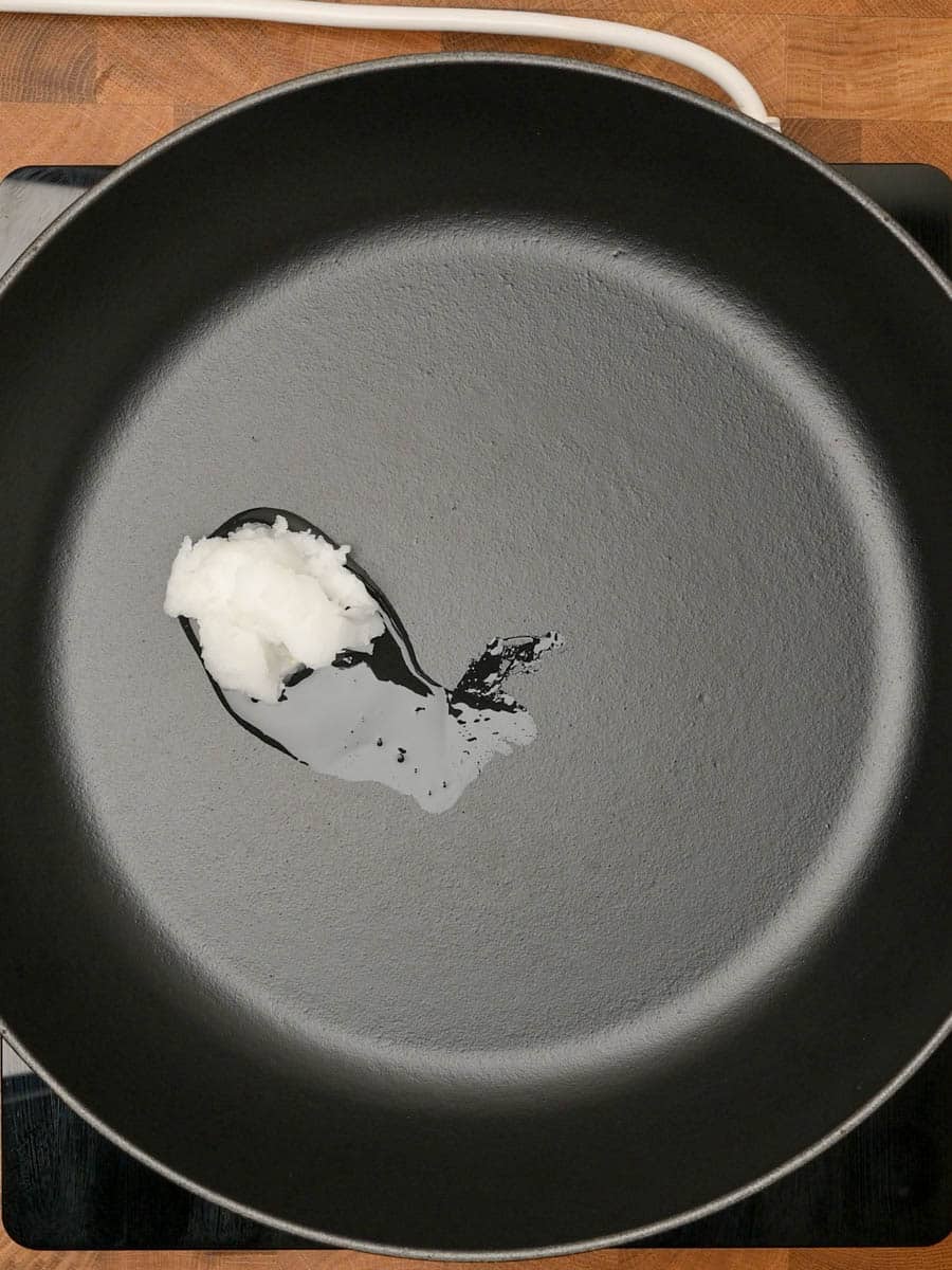 Empty cast iron skillet with a drizzle of coconut oil ready for cooking