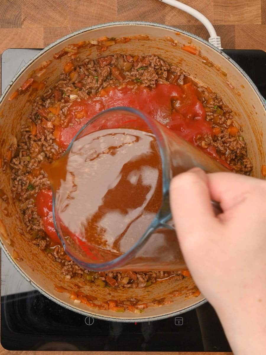 adding stock to a pasta dish