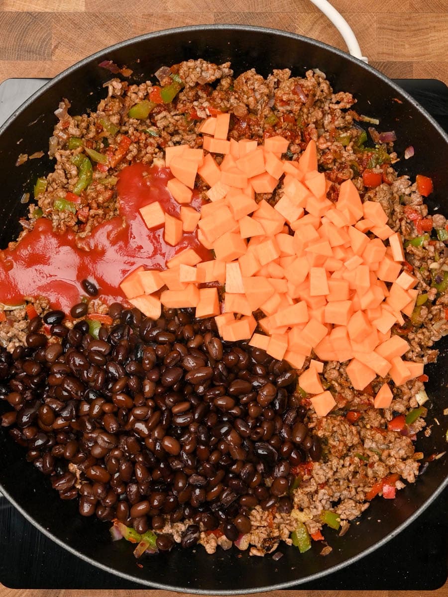 Mixing in black beans, sweet potato and tomato sauce