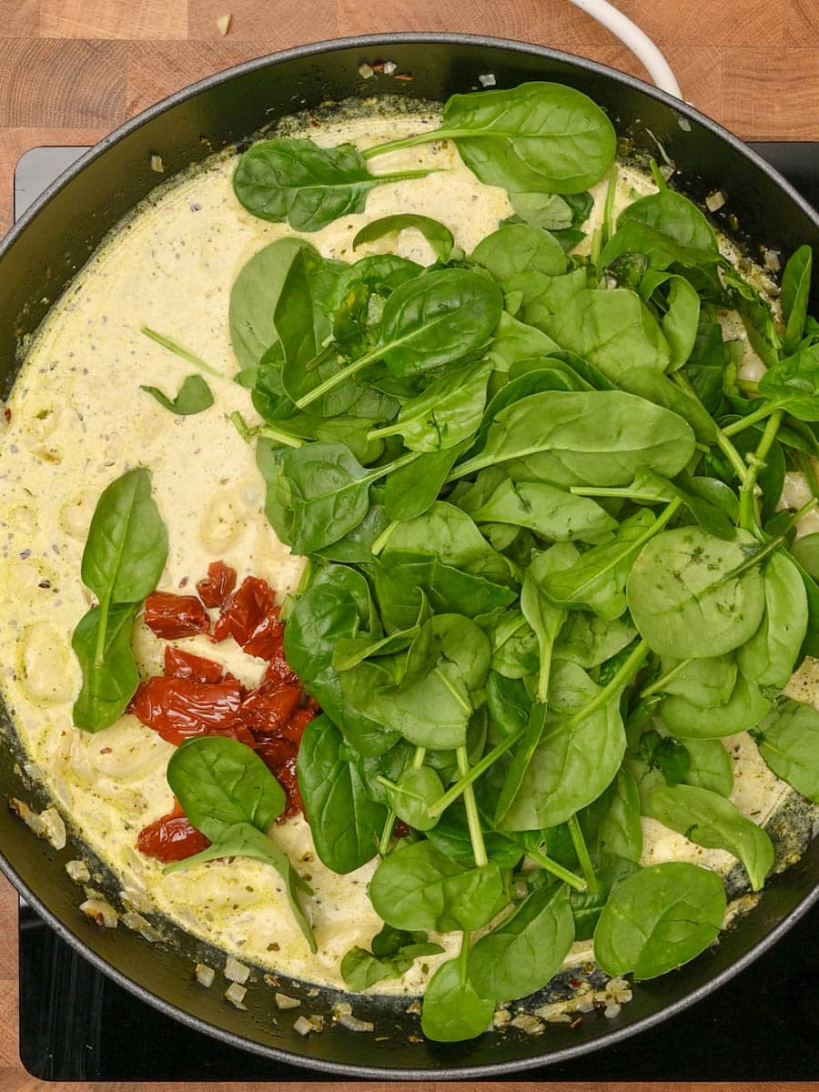 adding spinach to a pesto gnocchi bake
