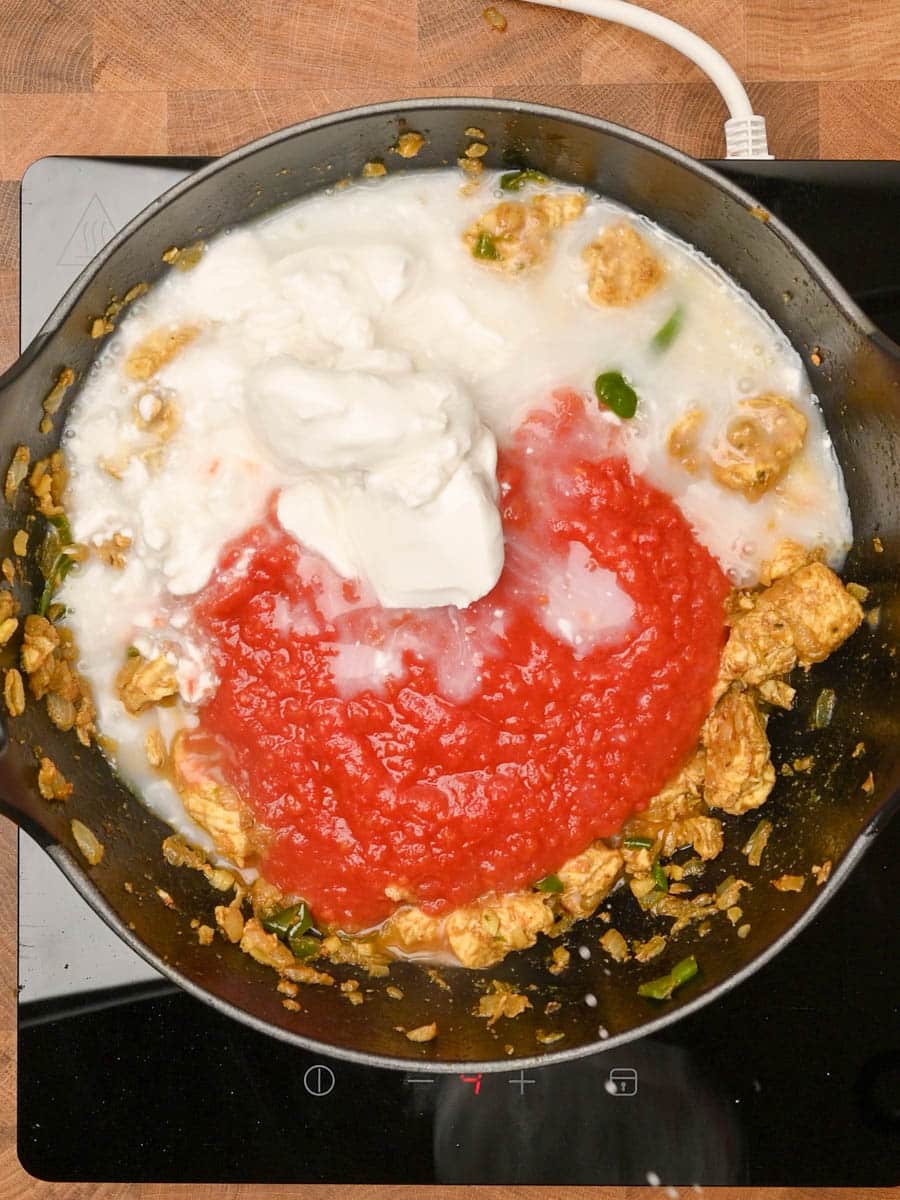 adding coconut milk to a chicken and prawn curry