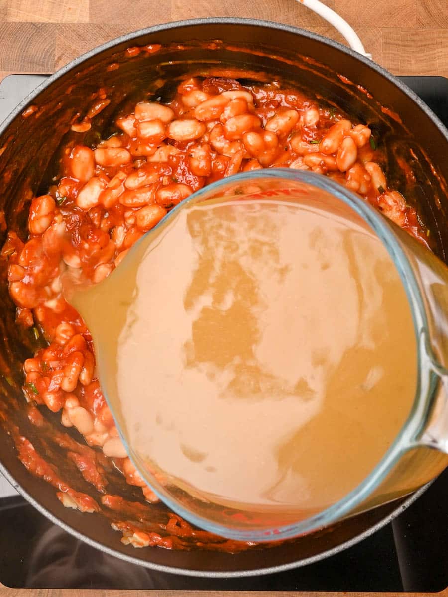 adding stock to a cannellini bean soup