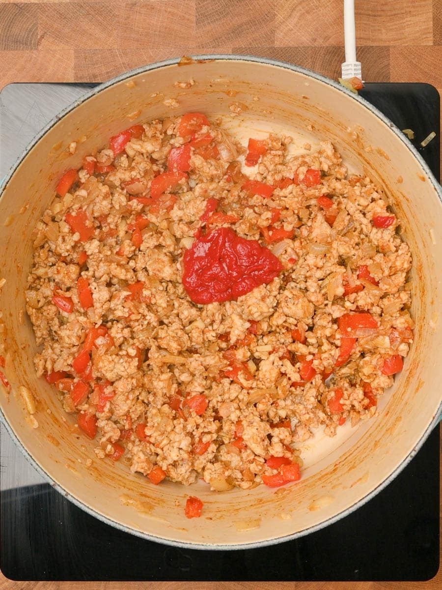 adding tomato paste to an American stew