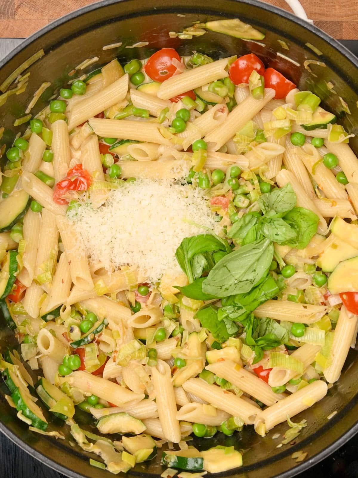adding parmesan and basil to the pot
