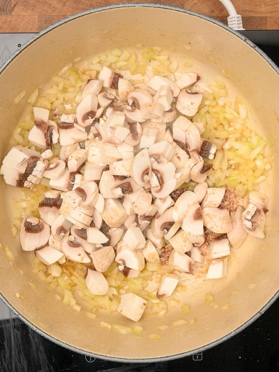 adding mushrooms to a chicken pasta bake