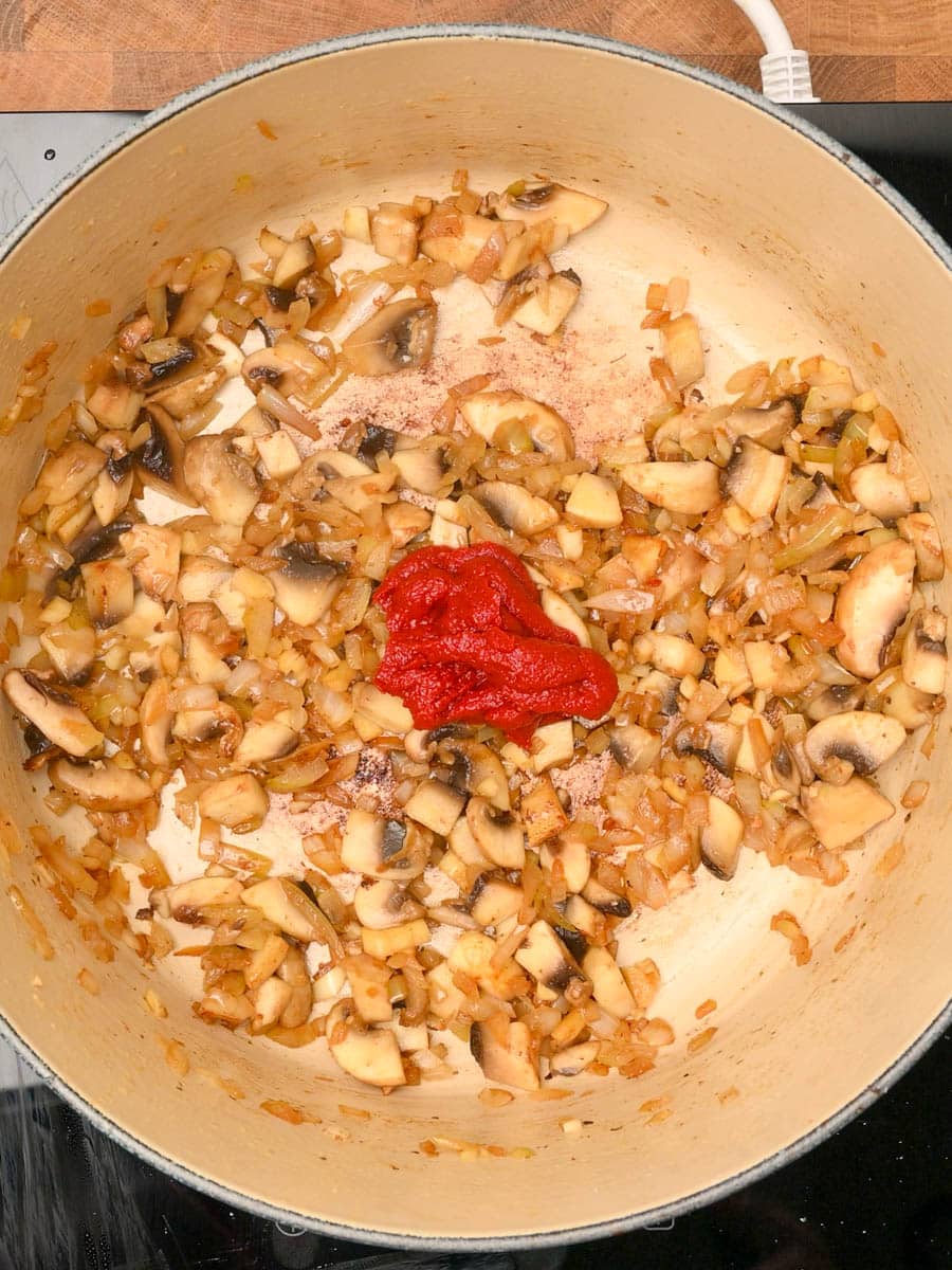 adding tomato paste to a chicken pasta bake