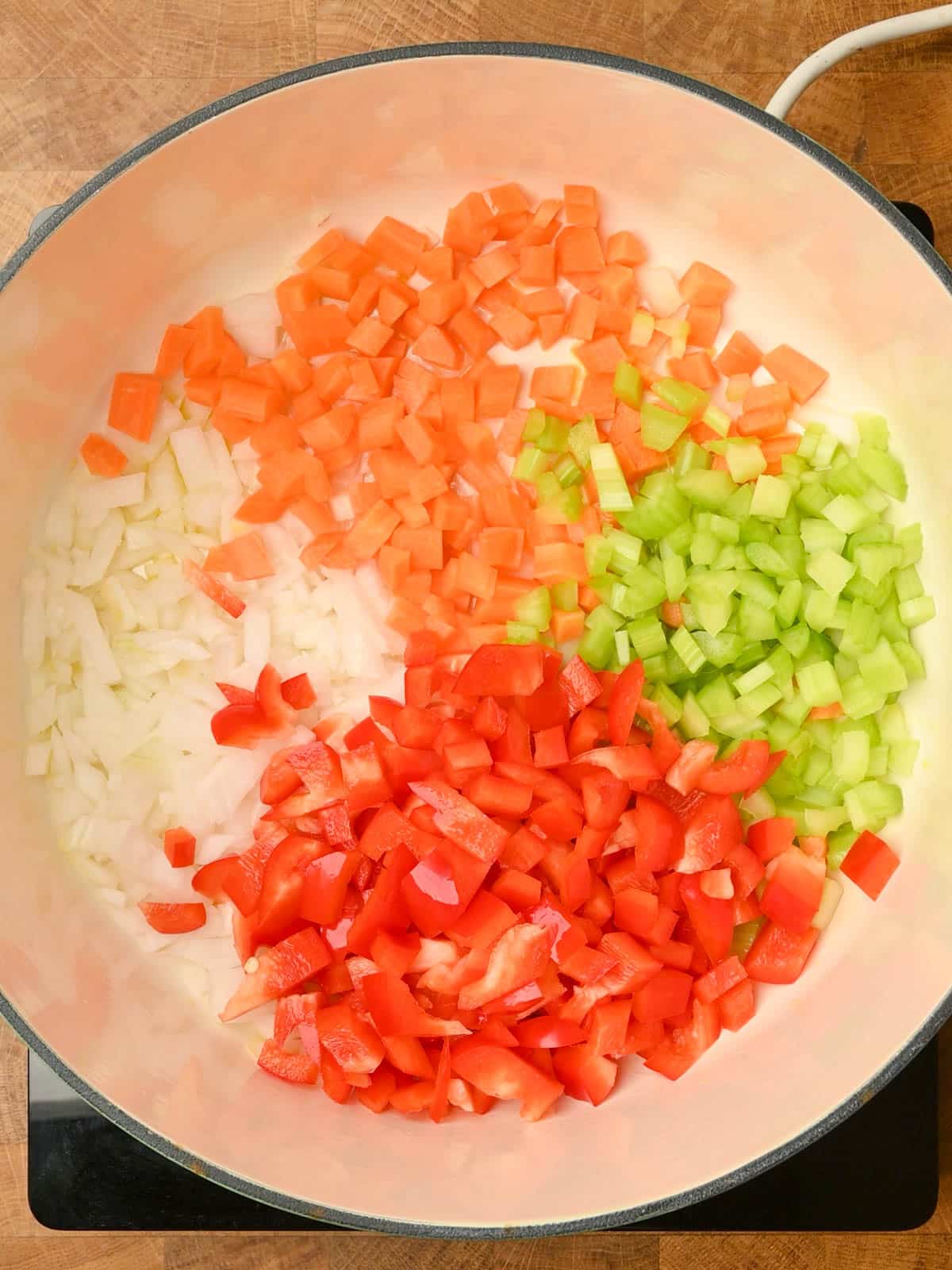 adding chopped veggies to a ground beef stew