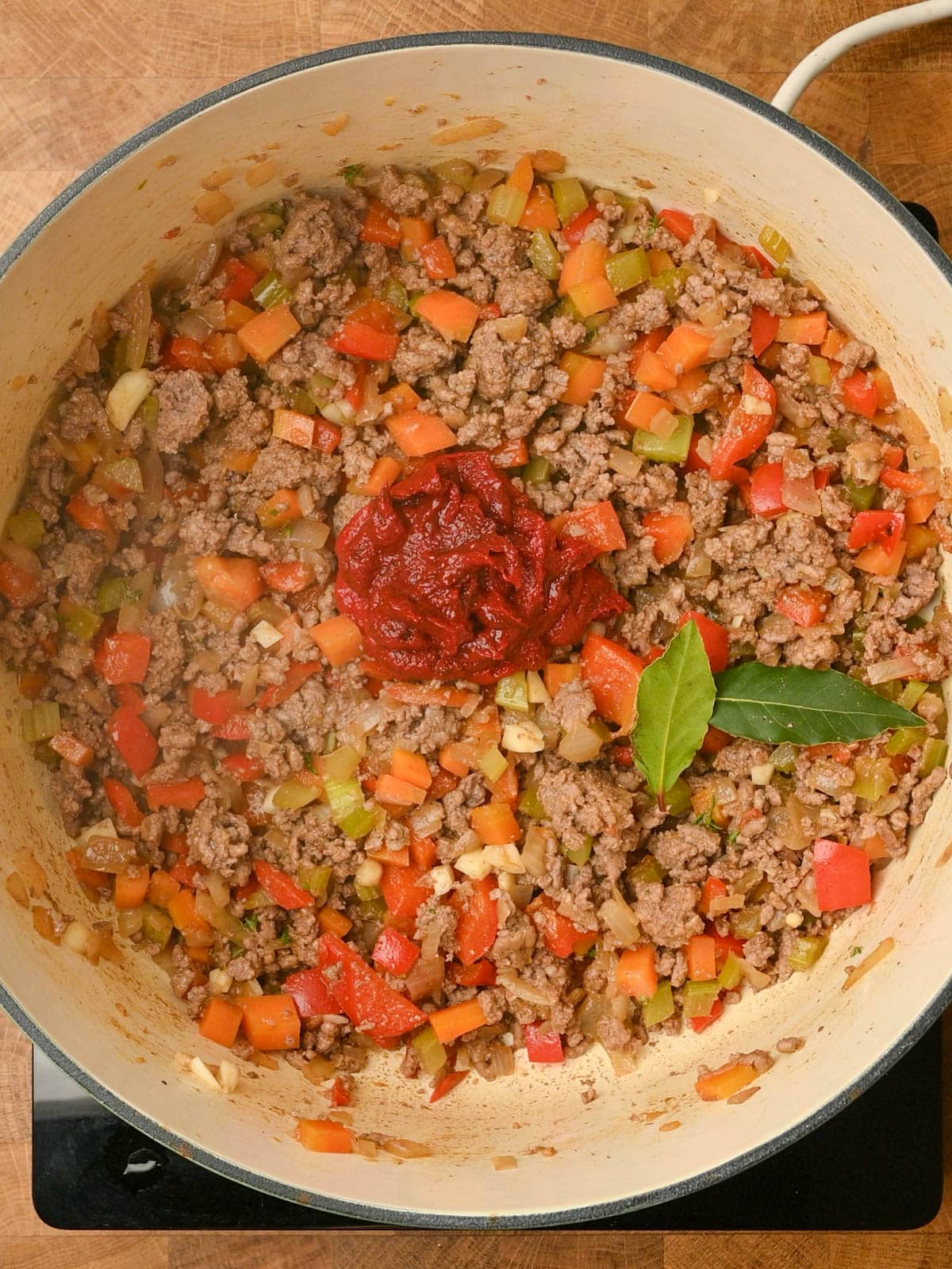 adding tomato paste to the cooking pot