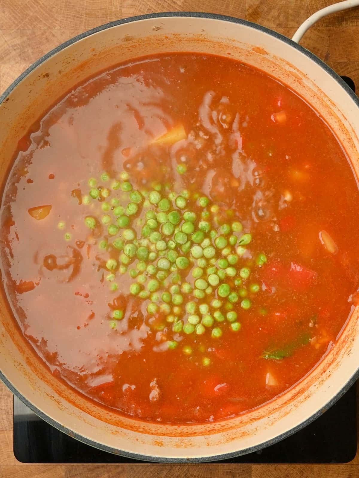 adding frozen peas and stock to the pot