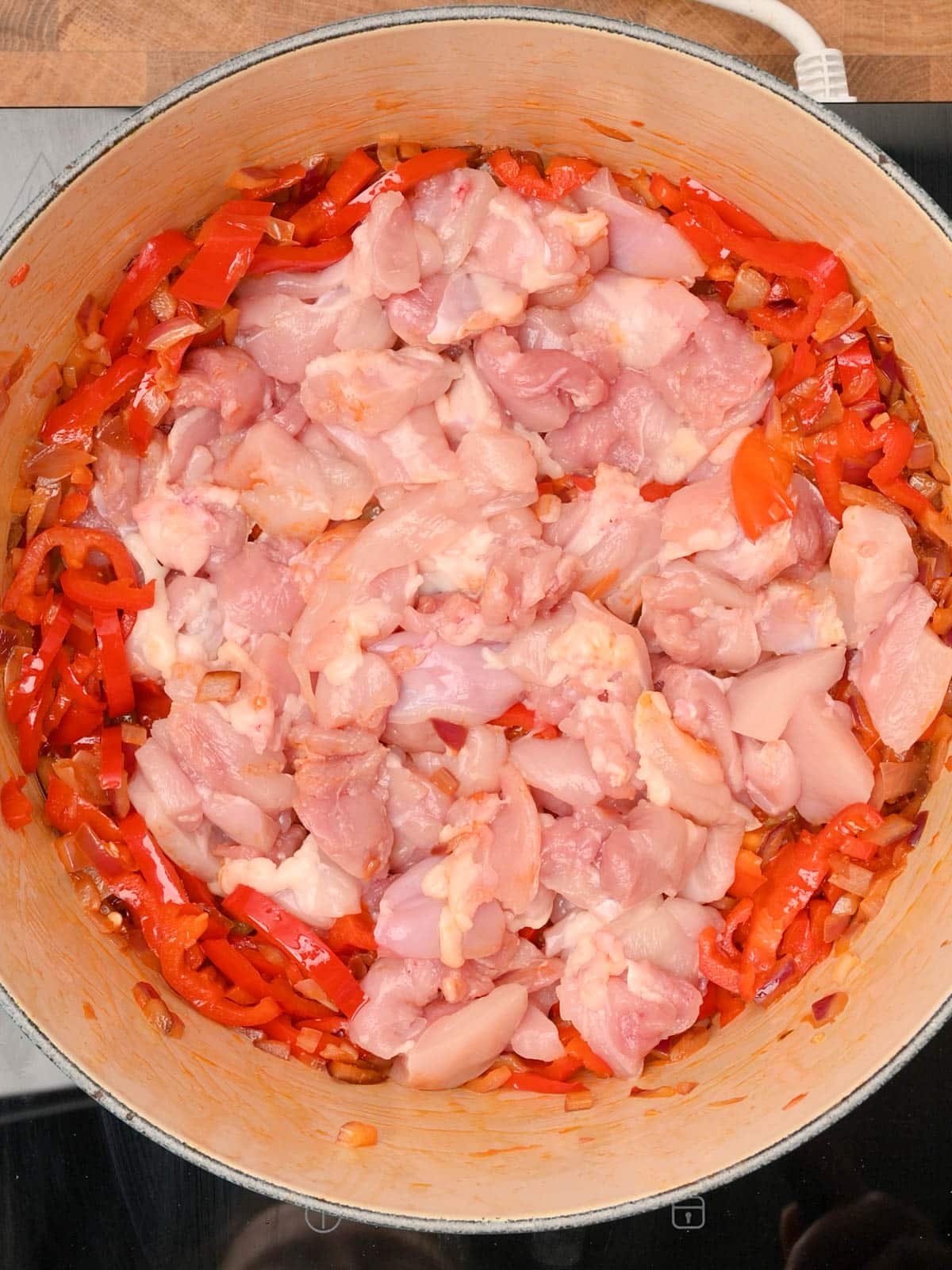 frying chicken and peppers in the pot