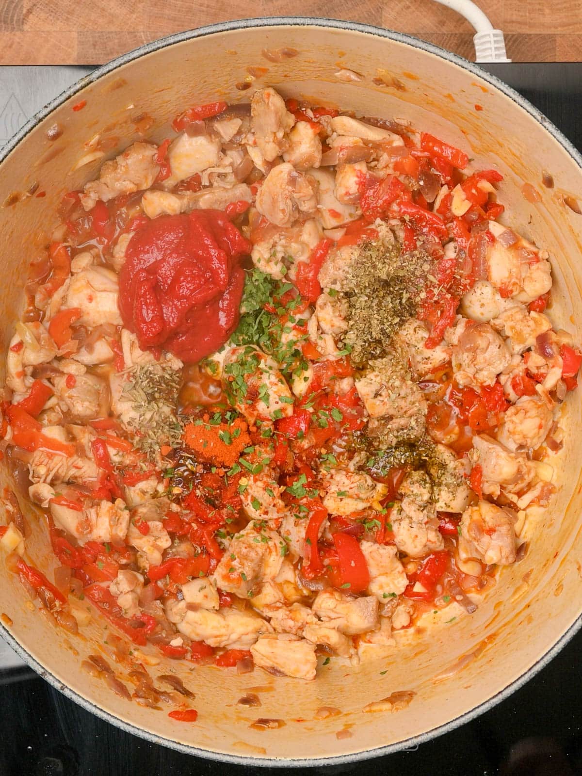 adding spices and tomato paste to chicken and chorizo rice