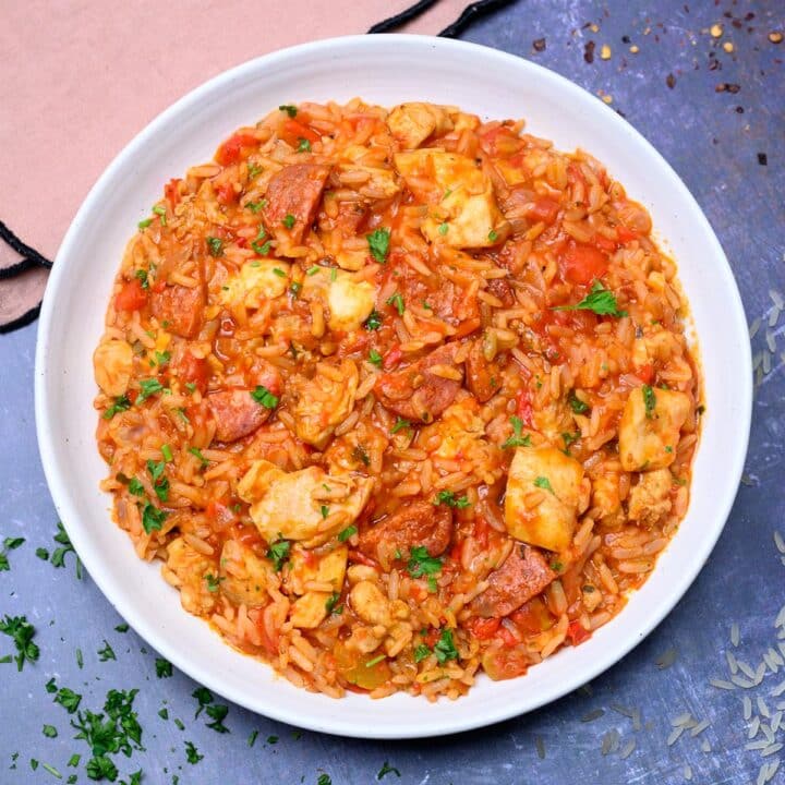 a white plate with chicken and chorizo rice