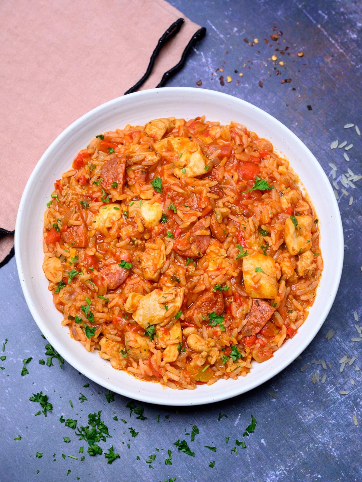 pieces of chicken and sausage with rice in a plate