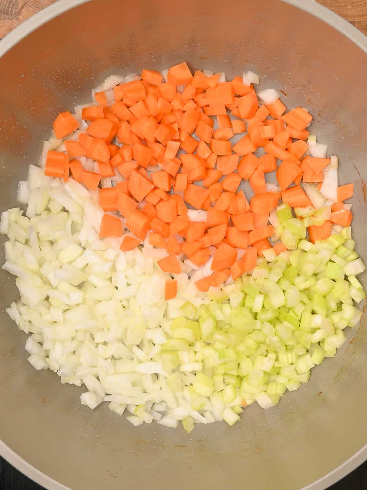 adding carrots, onion and celery to a bacon potato soup