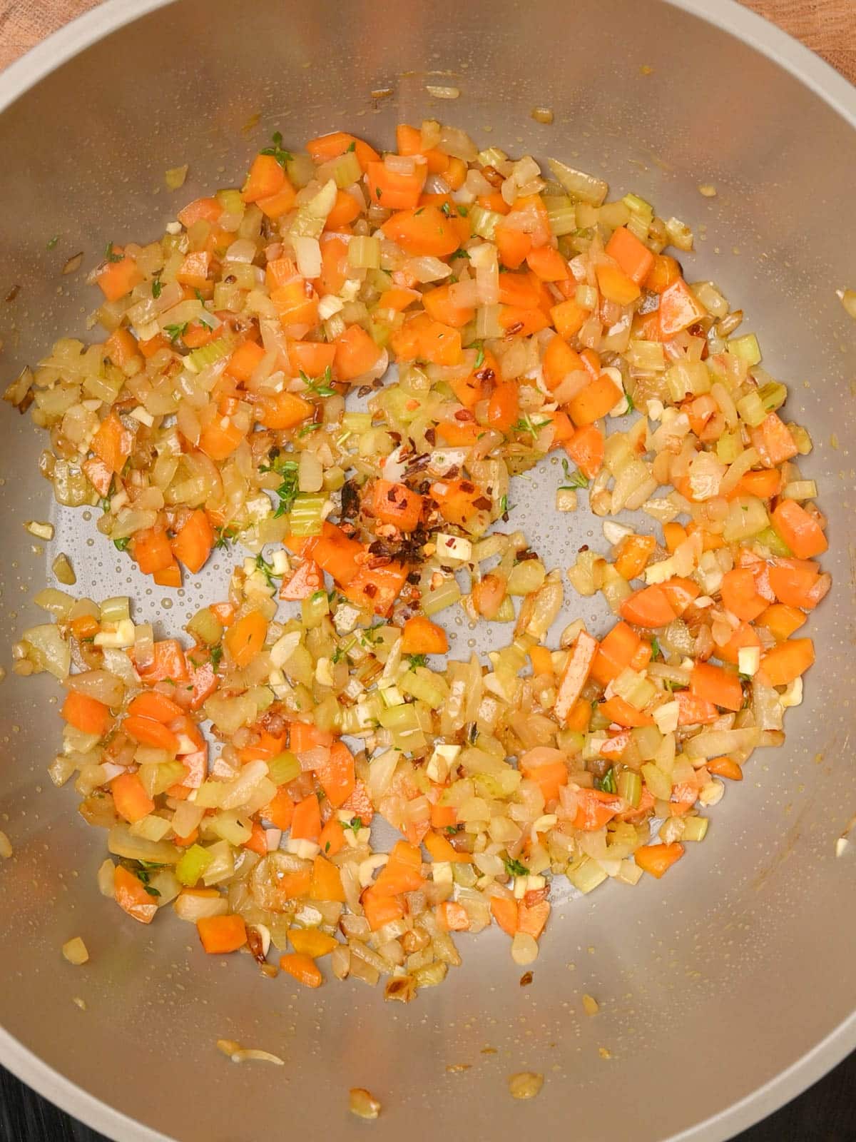 adding red chili flakes to a bacon potato soup