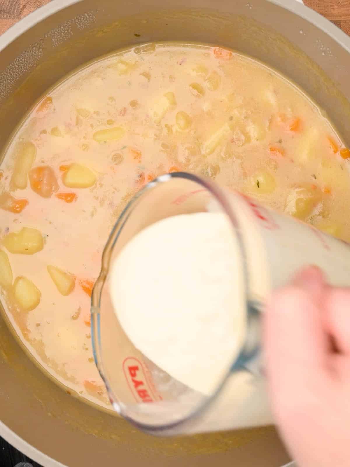 pouring soured cream to the cooking pot