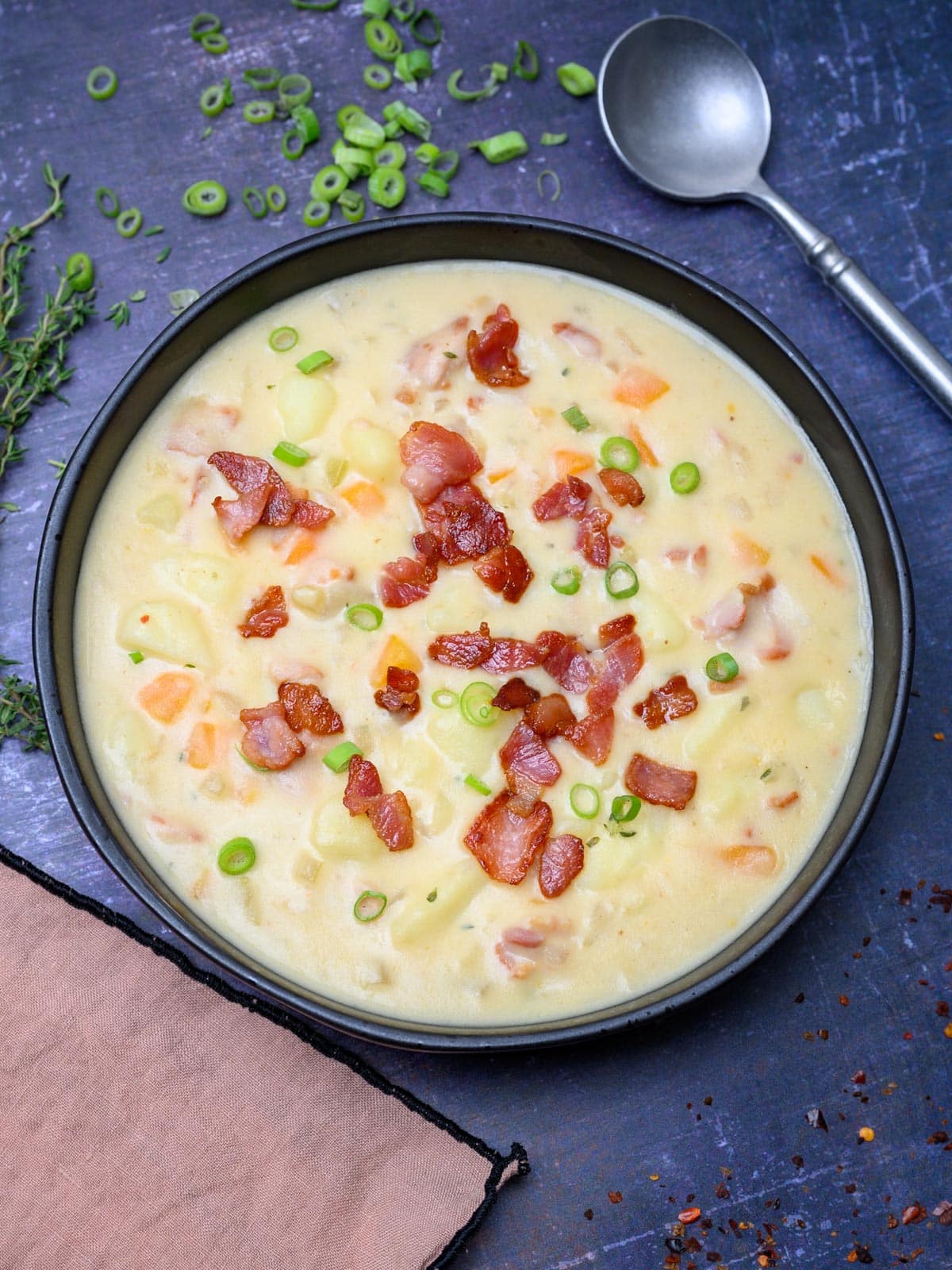 a bowl of a bacon potato soup with spring onions
