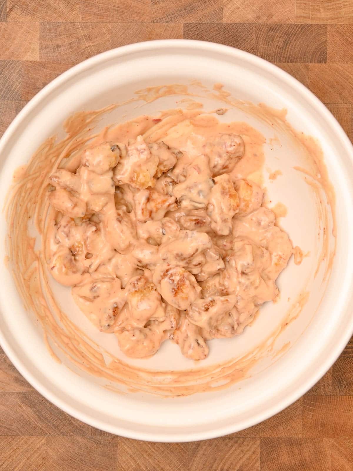 white bowl with chicken coated in sauce