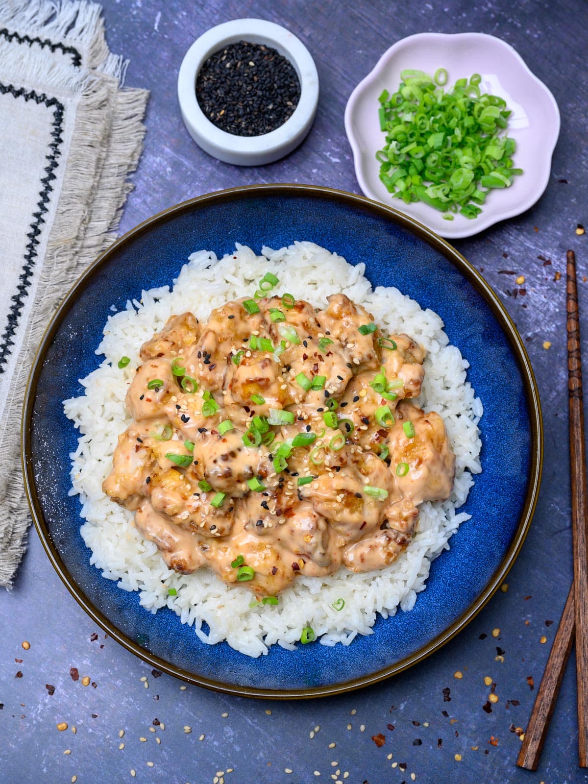 a blue bowl of rice with chicken and spring onions