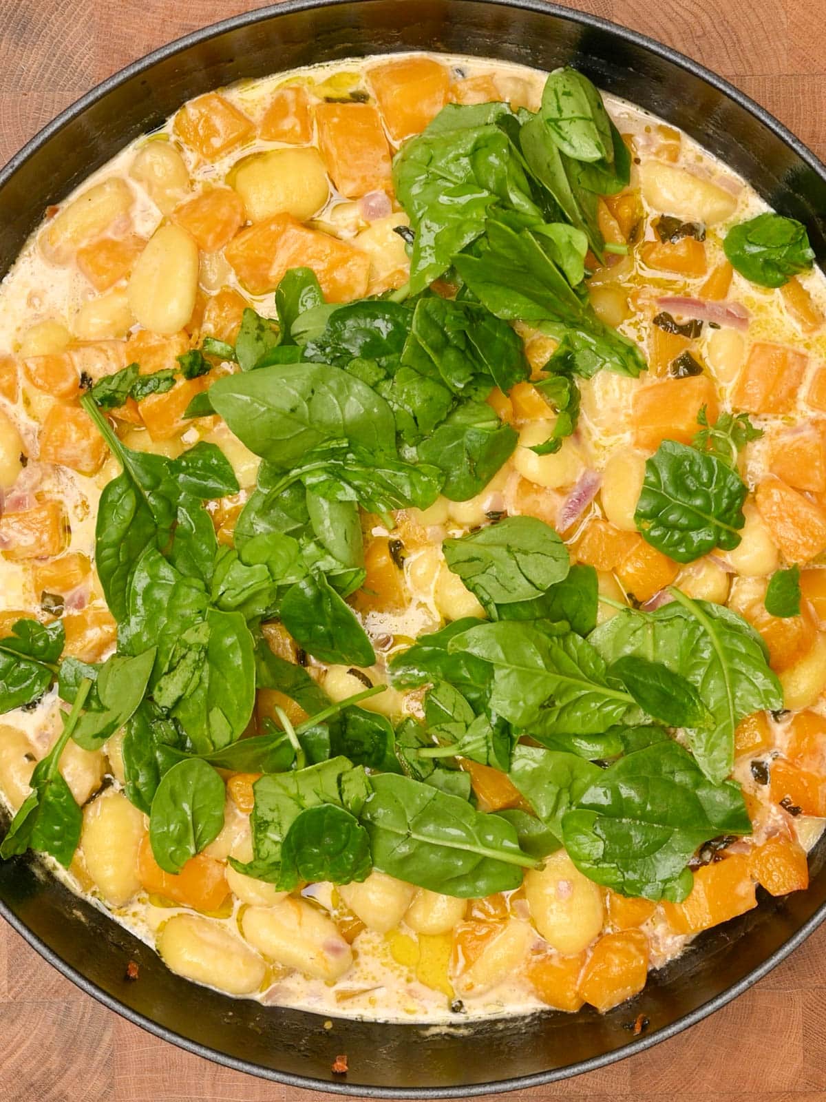 adding spinach to the cooking pan